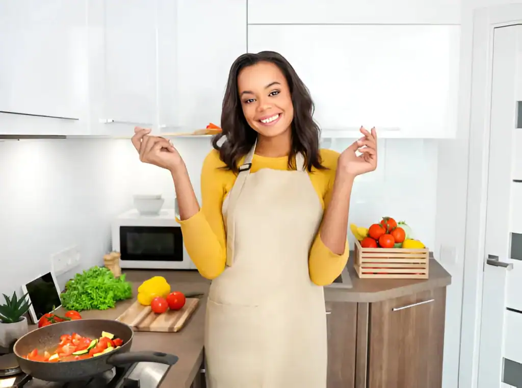 Smiling woman cooking in modern kitchen with fresh vegetables and ingredients.