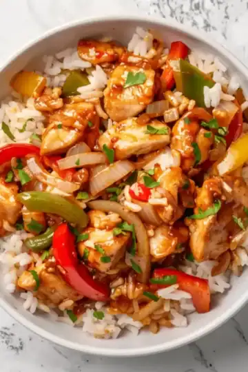 Fresh chicken stir-fry with bell peppers, onions, and rice, topped with herbs, ideal for dinner.
