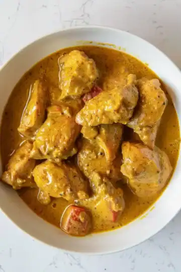 Delicious chicken curry with creamy, spiced sauce served in a white bowl.
